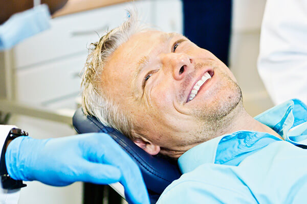 Man lying in dentist's chair while smiling