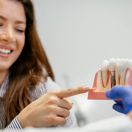 A dentist showing a model of a dental implant