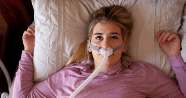 Woman lying in bed, having difficulty sleeping from CPAP equipment